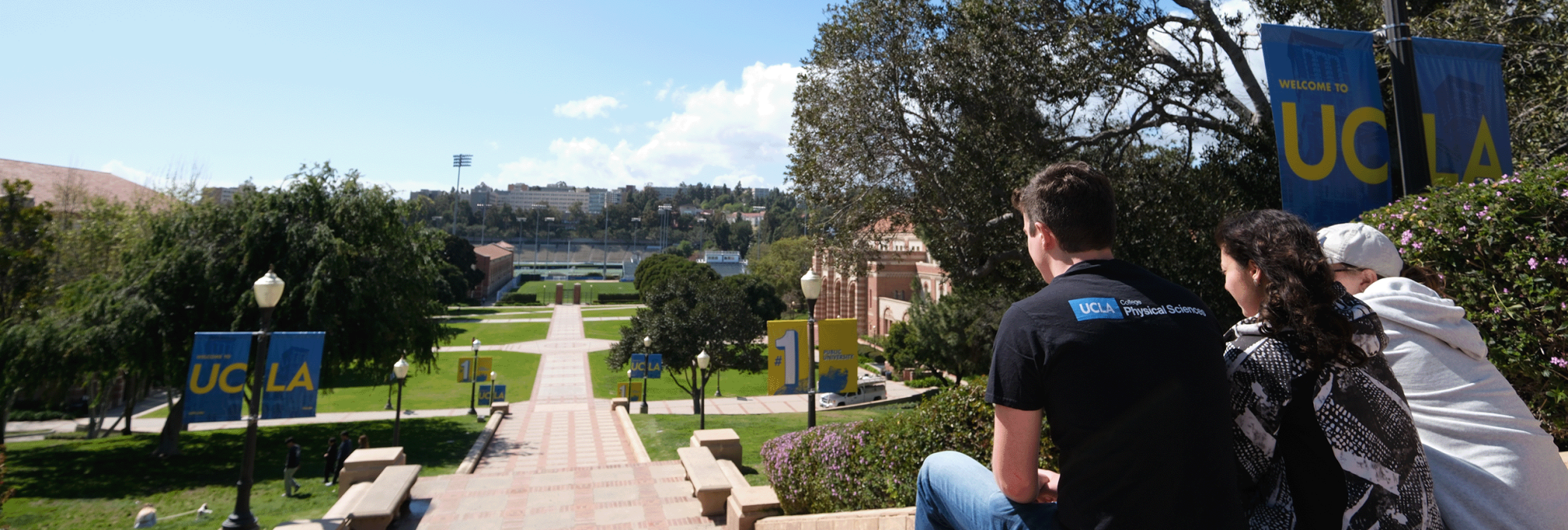Three students overlooking over Janss steps with banners stating UCLA in the background.