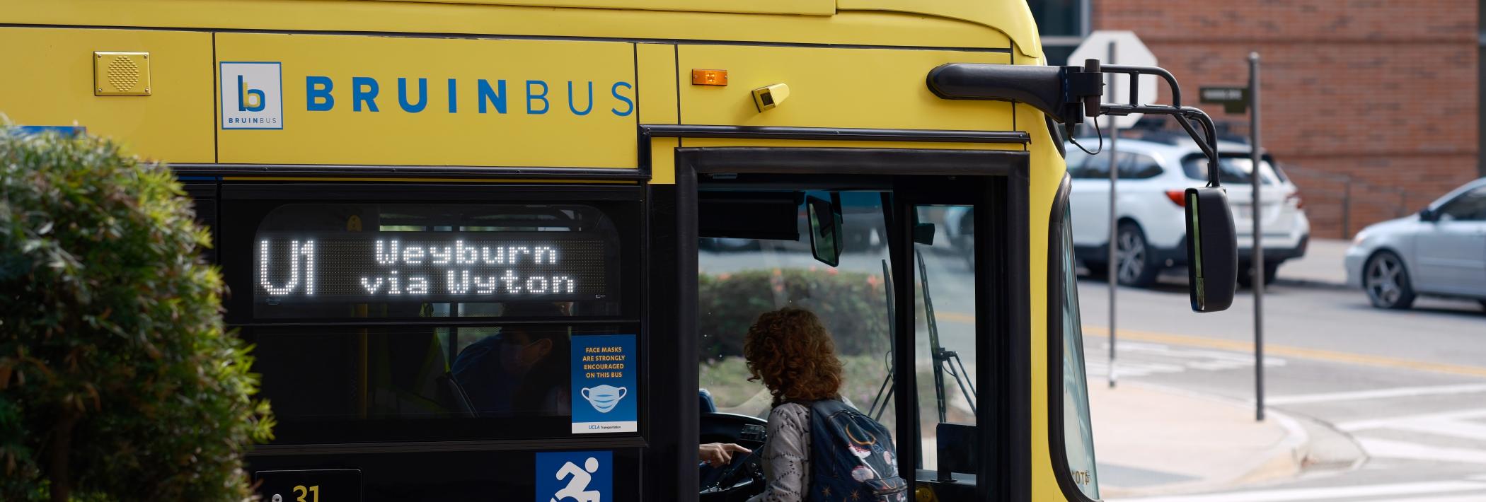 A student walks onto the Bruin Bus.