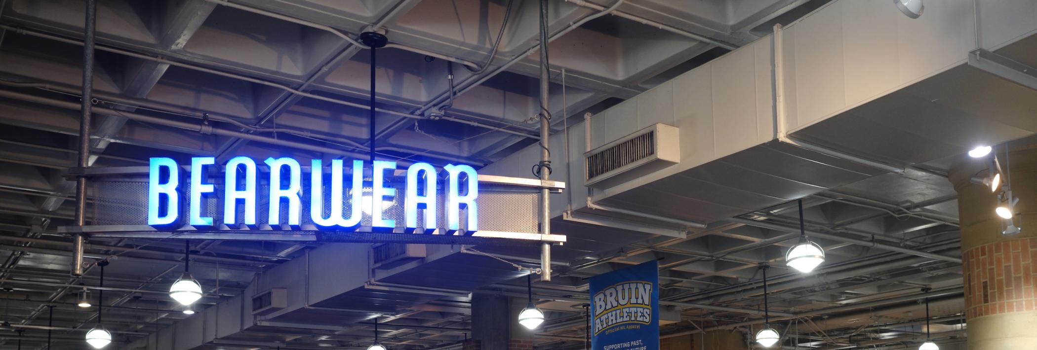 A sign saying Bearwear hanging from the ceiling around various clothing options